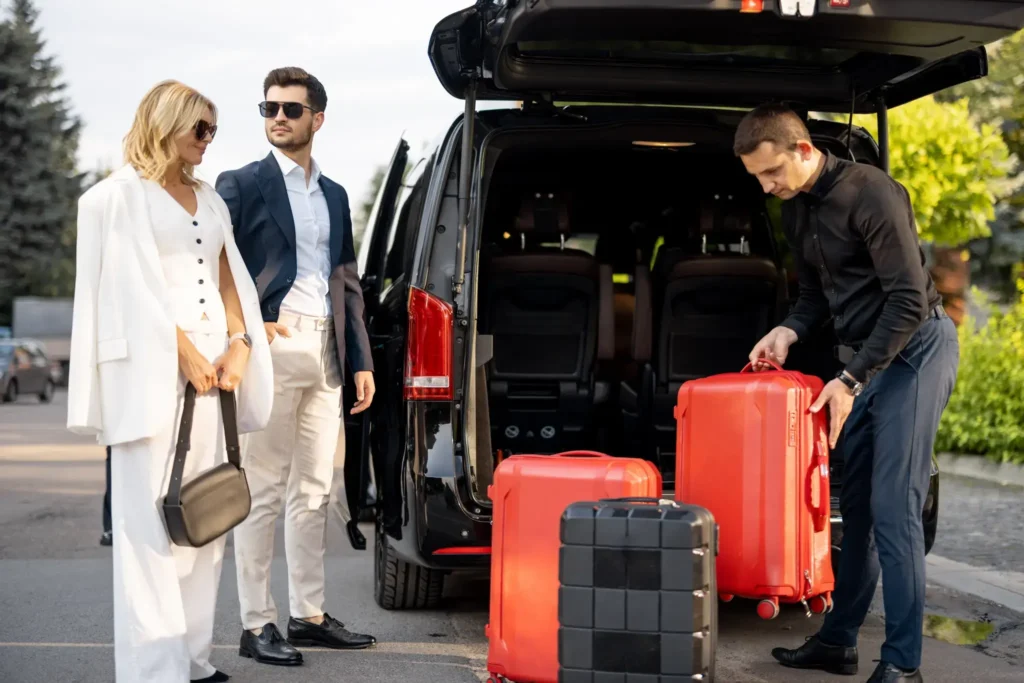 Luxury airport transfer by Perun Chauffeurs with a chauffeur loading luggage for an elegant couple